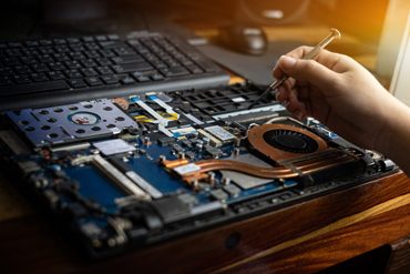 Hand technician repairing broken laptop notebook computer with a screwdriver